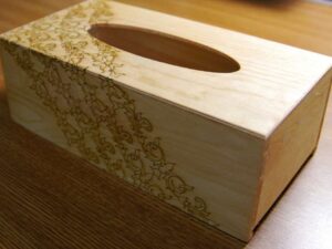 An engraving test on a wooden tissue paper box cover